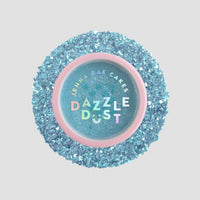 A round Jenna Rae Cakes Blue Sky Edible Glitter 5g shaker with a pink rim is filled and surrounded by sparkling blue glitter on a light gray background; sold as a package of 6.