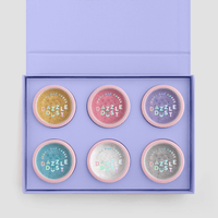 The Build Your Own Dazzle Dust Collection by Jenna Rae Cakes features six round pastel containers labeled Dazzle Dust, arranged in two rows of three inside a lavender gift box with MAKE LIFE DAZZLE on the lid.