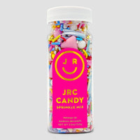 A clear plastic bottle filled with colorful candy sprinkles, featuring a bright pink label with a yellow smiley face and the text Home Baker Bundle by Jenna Rae Cakes.