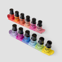 The Jenna Rae Cakes x Colour Mill Pack by Jenna Rae Cakes features ten food coloring bottles in assorted colors, arranged in two rows on rainbow-gradient cardboard trays against a light gray background.