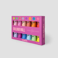 The Jenna Rae Cakes x Colour Mill Pack features twelve bright food coloring bottles in a purple box with colorful smiley faces and COLOUR MILL and Jenna Rae Cakes on the front.