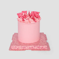 Pink cake with pink buttercream and pink chocolate shards on top.