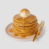 A light plate holds pancakes topped with ice cream and Jenna Rae Cakes’ Liquid Pumpkin Spice (package of 6), drizzled as syrup, beside a gold fork on a plain light background.