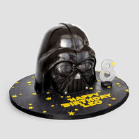 One-of-a-Kind Cakes by Jenna Rae Cakes: A Darth Vader helmet birthday cake with yellow stars, “Happy Birthday Leo” message, and a silver number 8 candle on a round black base.