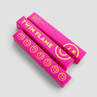 Two bright pink rectangular boxes labeled Twin Flame Perfume in bold yellow text, featuring yellow smiley faces and J R in a circle, from Jenna Rae Cakes, displayed on a light gray background.