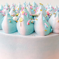 The Cotton Candy Cake by Jenna Rae Cakes features pastel blue and pink frosting swirls, colorful sprinkles, gold flecks, and sugar pearls for a festive, whimsical look.