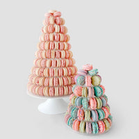 Jenna Rae Cakes’ Dessert Tables feature two cone-shaped macaron towers on white stands: one with pink and cream macarons, the other smaller tower with pastel blue, pink, and purple macarons.