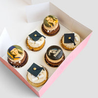 Jenna Rae Cakes Grad Works Cupcakes come in a pink box of six: three topped with edible famous painting images, and three decorated with black graduation caps and diplomas on white frosting.