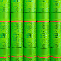 Rows of vibrant green cylindrical containers of Jenna Rae Cakes Liquid Candy Melon, adorned with decorative patterns and white text, are stacked closely together to create a visually striking, repeating display.