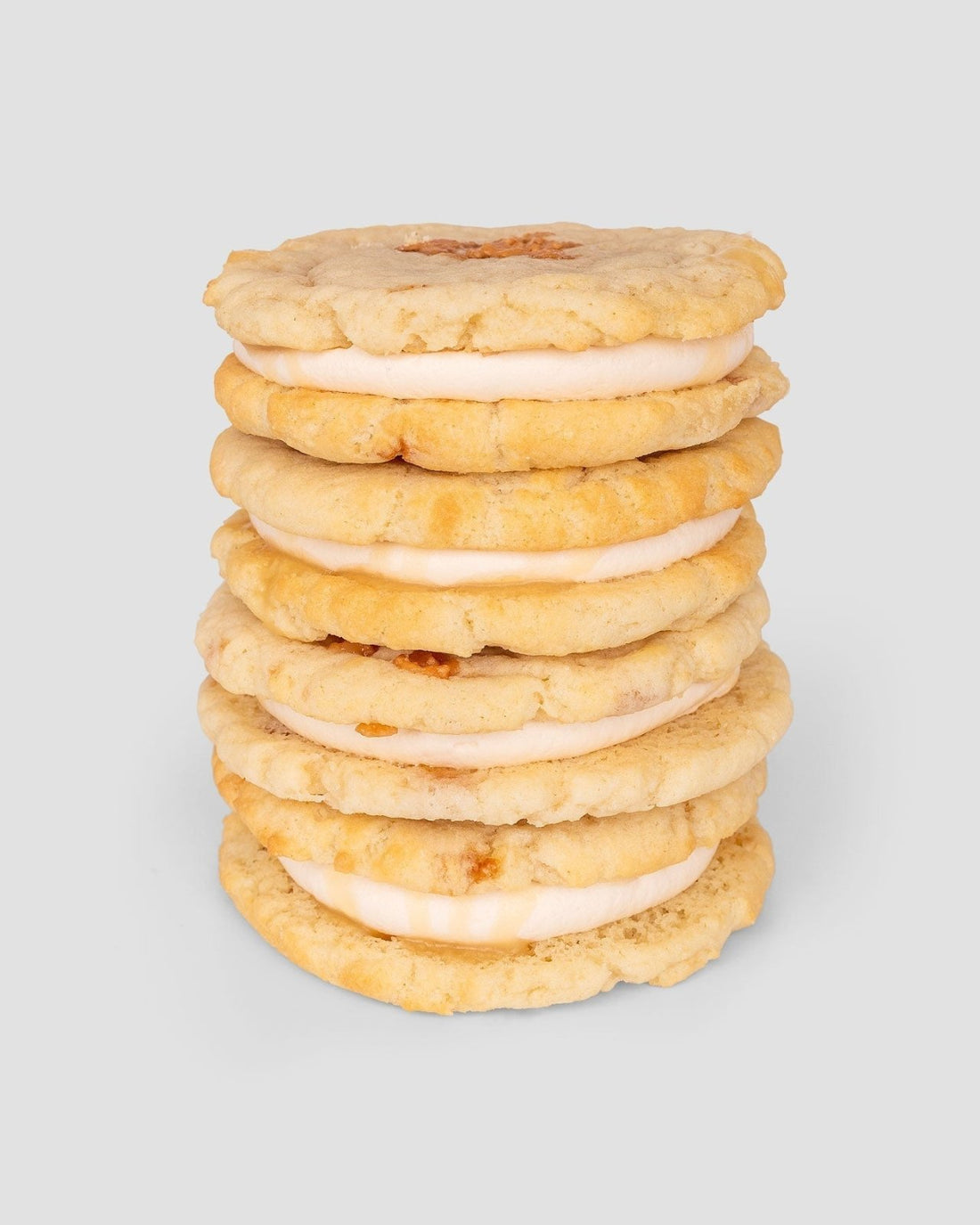 A stack of six $165 JRC Gift Bag sandwich cookies by Jenna Rae Cakes, with creamy filling between two golden, crumbly cookies, set against a plain light gray background.