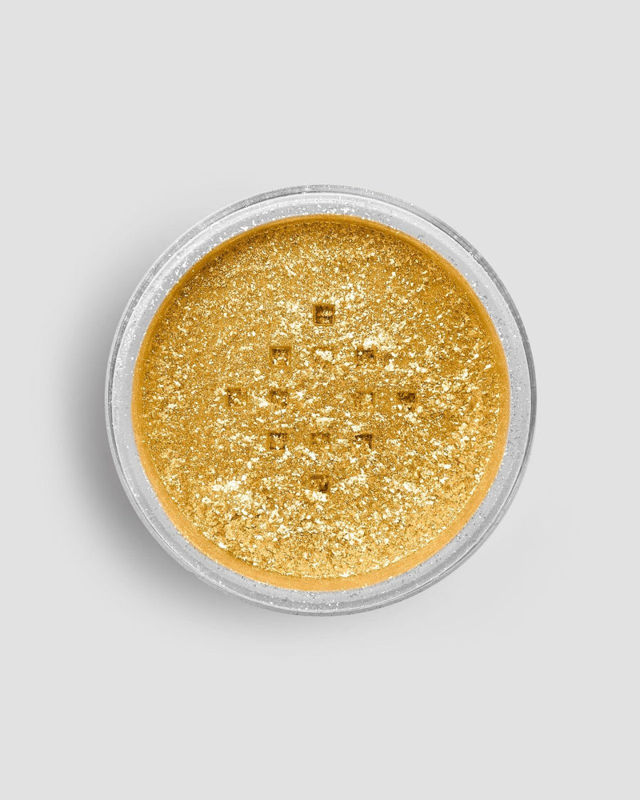 A small, round container of Jenna Rae Cakes FND TESTING - 24k Magic Edible Glitter (Copy) filled with loose, shimmery gold glitter is viewed from above against a plain light gray background.