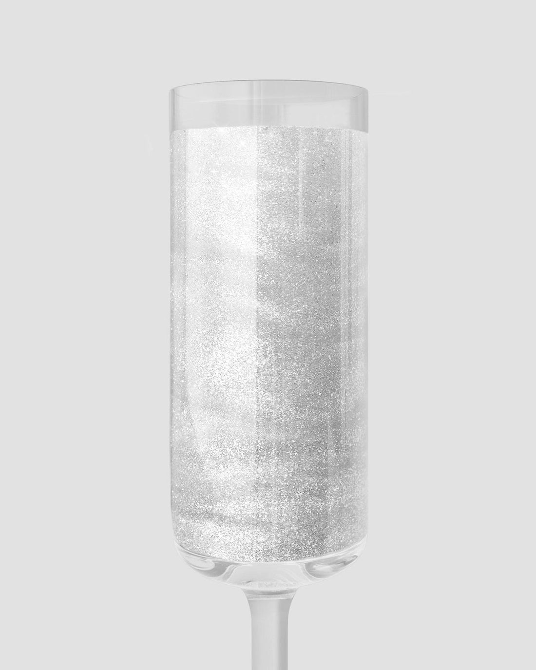 A clear champagne glass filled with sparkling Jenna Rae Cakes Diamond Edible Glitter shines against a light gray backdrop. Shown: 20g container, package of 3.