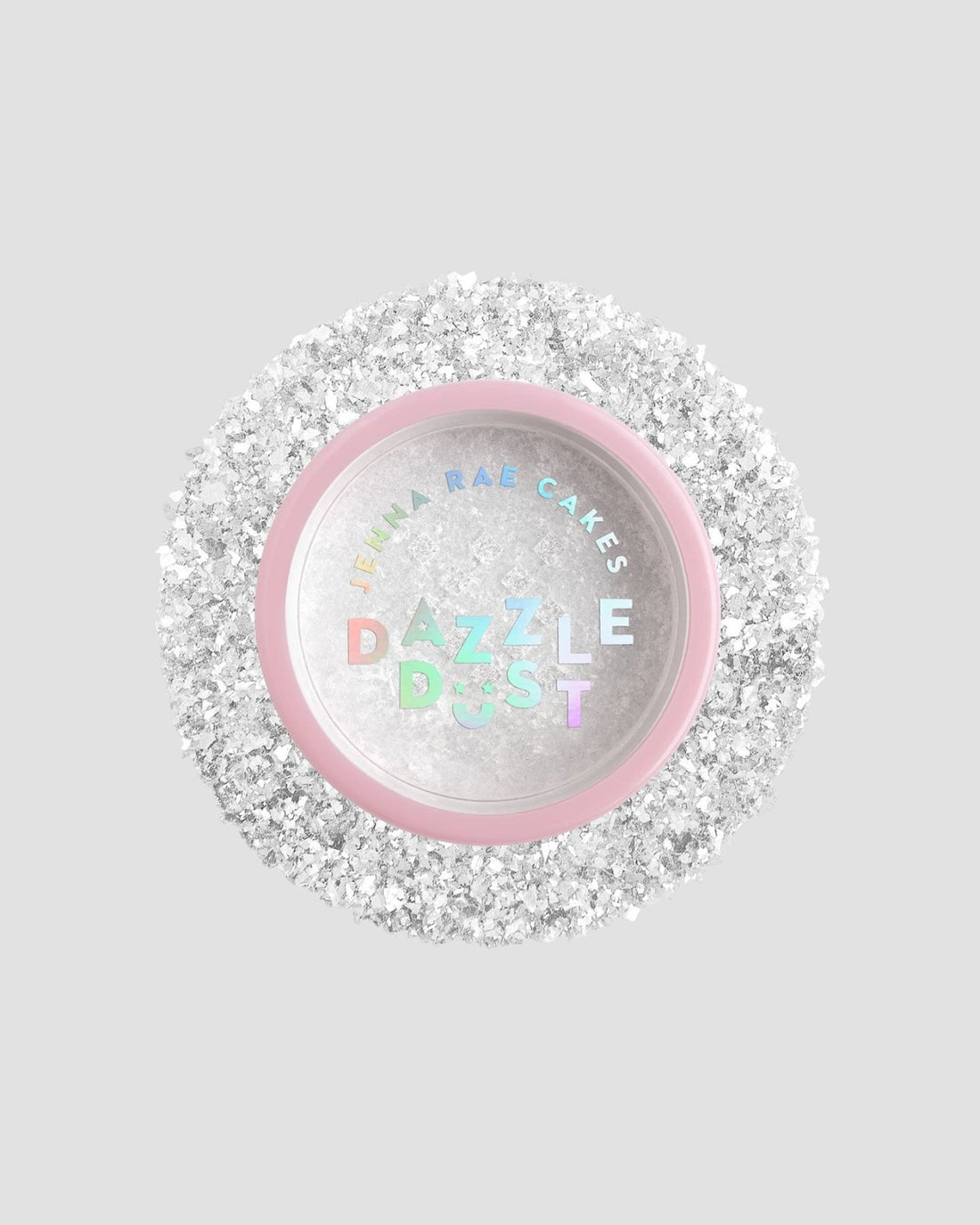 A small round container with a pink rim and clear lid labeled Jenna Rae Cakes Dazzle Dust Best Seller Trio, filled with fine, sparkly white glitter, sits on a light gray background.