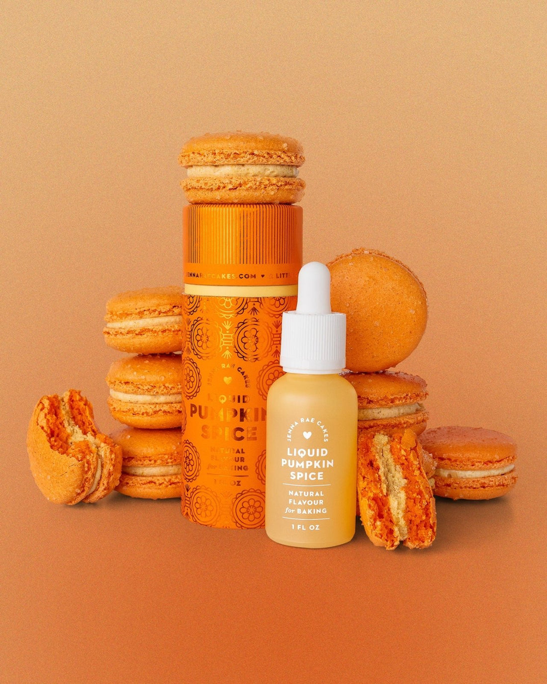 Orange pumpkin macarons surround a bright orange canister and a small dropper bottle, both labeled Liquid Pumpkin Spice by Jenna Rae Cakes, set against an orange gradient background.