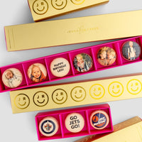 The Macaron Message Gift Box from Jenna Rae Cakes features rectangular yellow boxes with custom macarons displaying smiling faces, children’s photos, messages like HAPPY BIRTHDAY LEO!, GO JETS GO!, and Winnipeg Jets logos.
