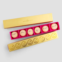 The Will You Be My... Gift Box by Jenna Rae Cakes features six macarons with “Will you be my bridesmaid?” in cursive, plus an open box with six smiley face and JR initial macarons, all set against a light gray background.