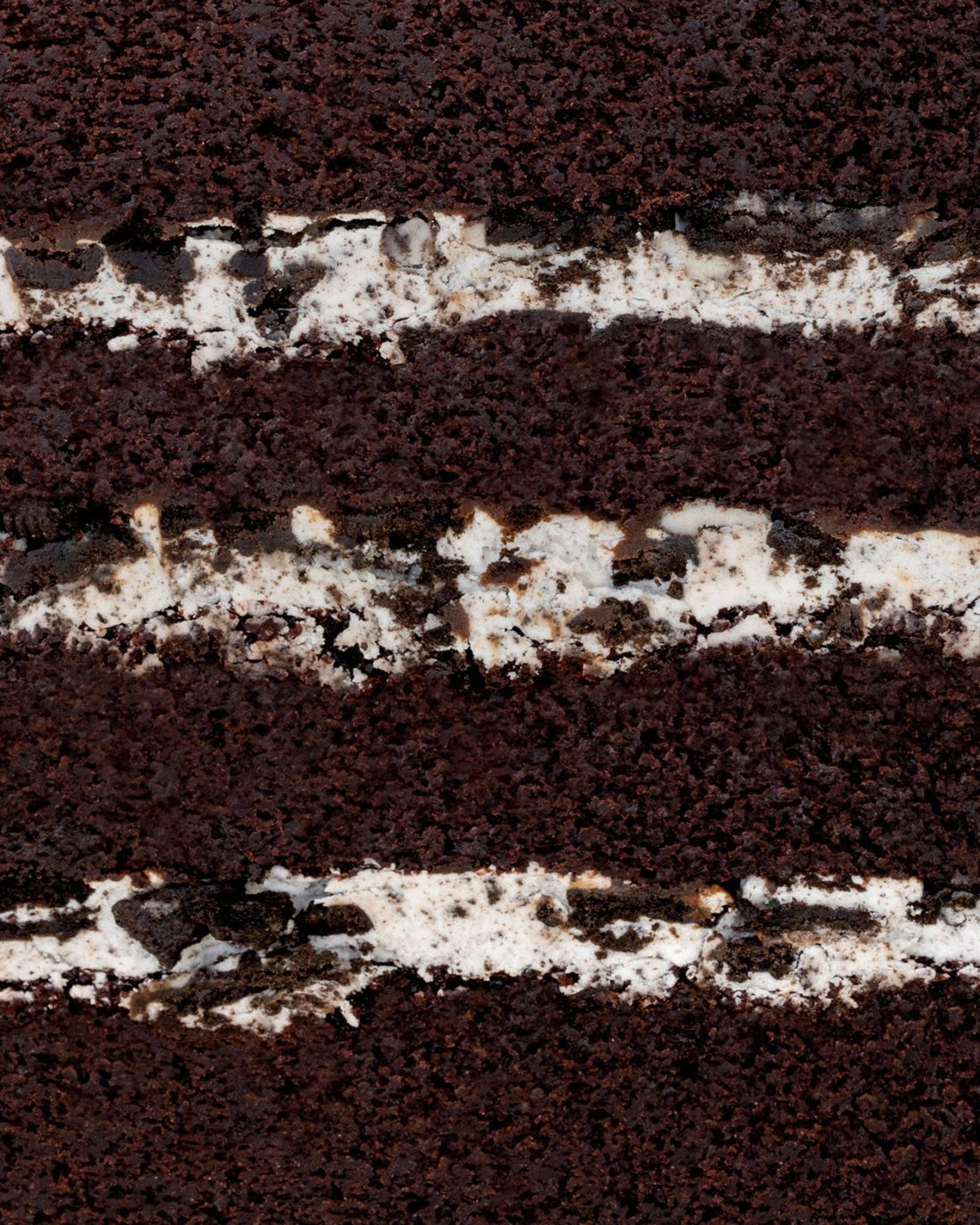 Close-up of the Chocolate Oreo Cake by Jenna Rae Cakes, showing layers of dark chocolate sponge and white cream filling with Oreo cookie pieces blended into the cream.
