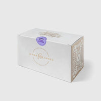 A white rectangular Cookie Sandwich Gift Box from Jenna Rae Cakes, featuring a gold logo on the front, decorative side patterns, and a purple Baked Cakes sticker on top.