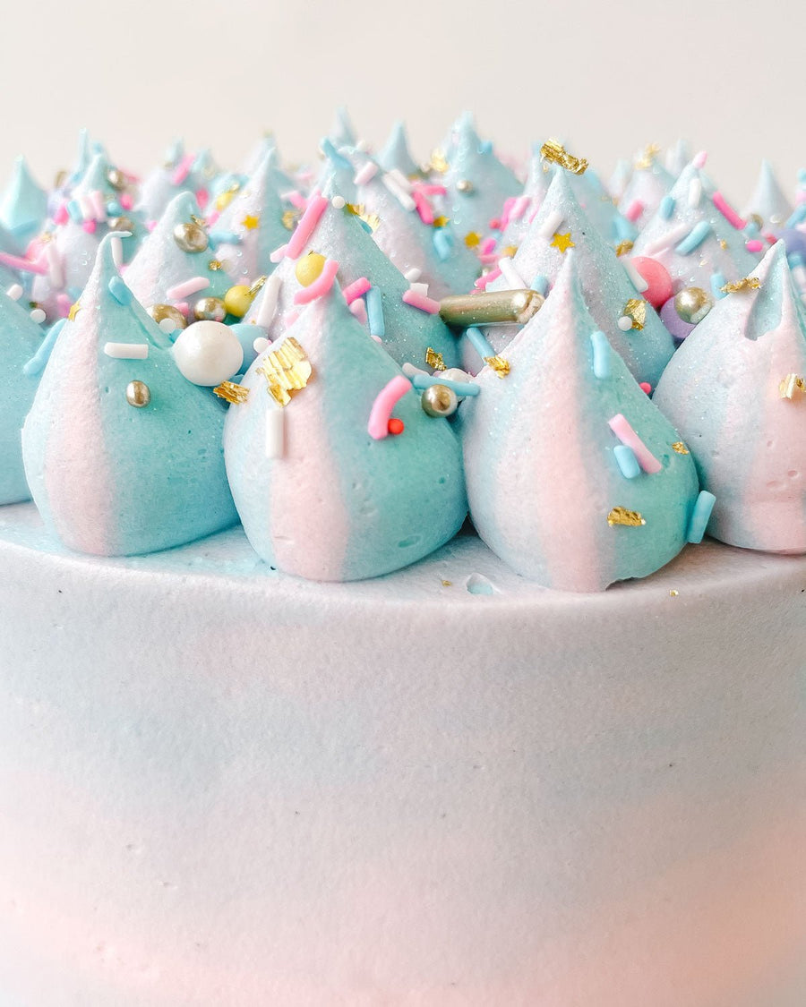 The Cotton Candy Cake by Jenna Rae Cakes features pastel blue and pink frosting swirls, colorful sprinkles, gold flecks, and sugar pearls for a festive, whimsical look.