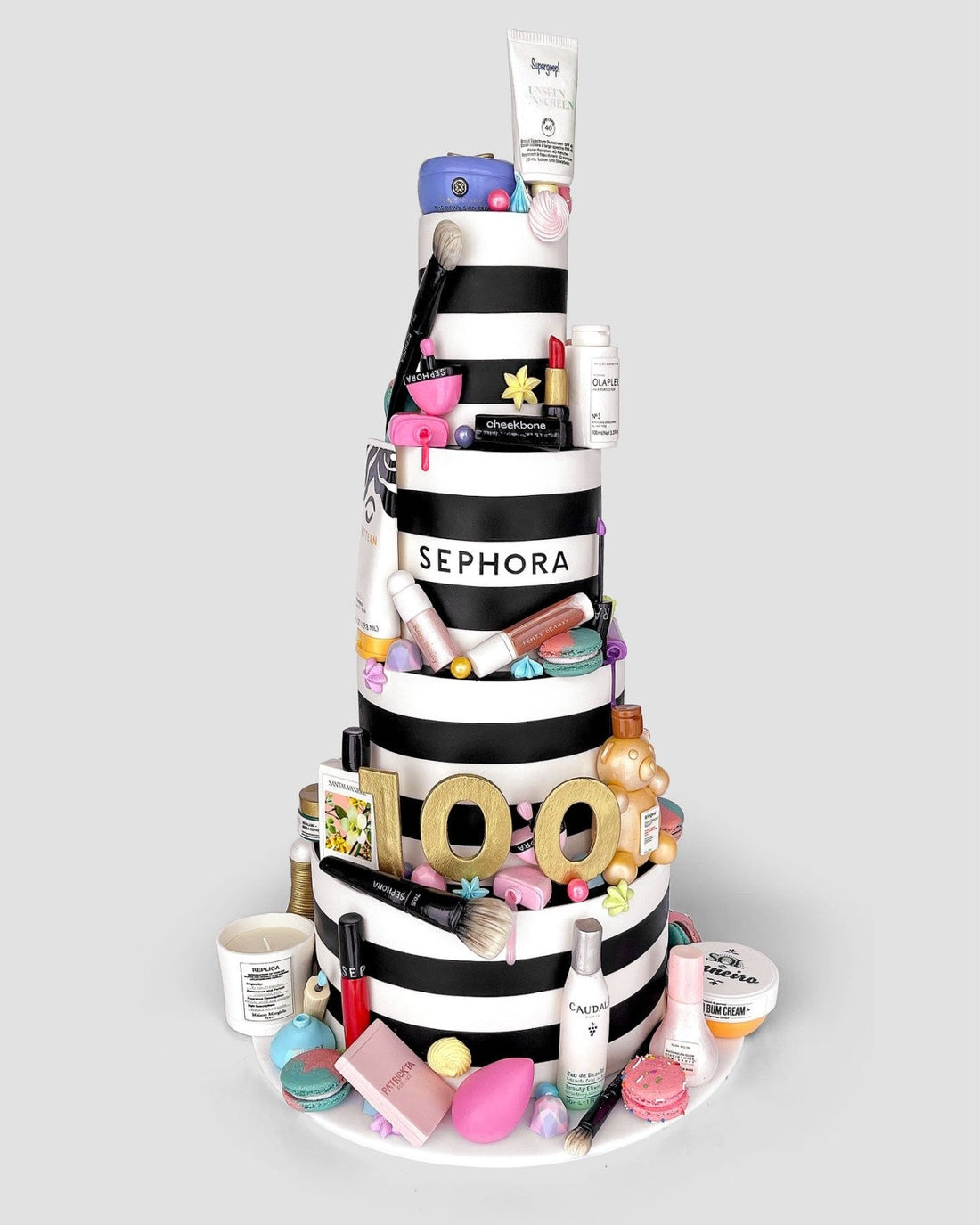Jenna Rae Cakes’ One-of-a-Kind Cakes features a tiered black-and-white striped cake, adorned with Sephora-themed fondant, topped with makeup and skincare items, and finished with a gold 100 to celebrate Sephora’s 100th anniversary.