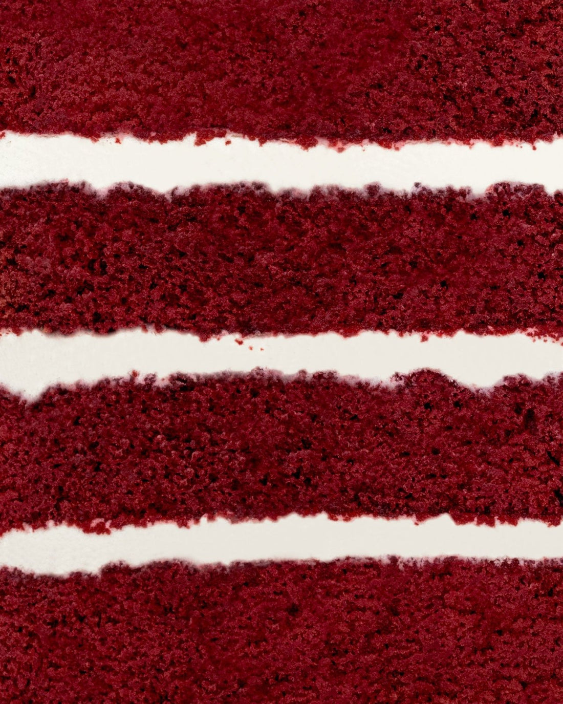 Close-up of Jenna Rae Cakes Red Velvet Cake, highlighting its moist, red-brown layers and thick, smooth cream cheese frosting in between.