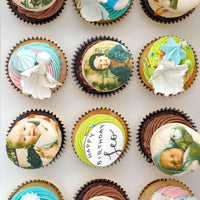 The Works Cupcakes by Jenna Rae Cakes: a box of colorful cupcakes, some with pastel swirls and white chocolate shards, others featuring edible baby and child images, plus one with Happy Birthday Joe on top.