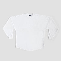 A Jenna Rae Cakes White and Silver Spirit Jersey is laid flat on a light gray background, featuring long sleeves, ribbed cuffs, and a small dark tag on the lower side seam. No visible patterns or logos are present.