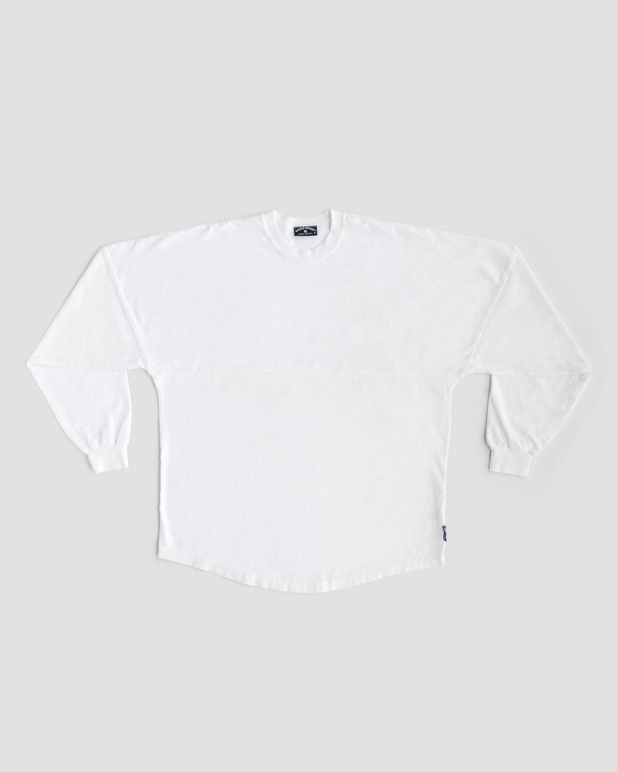 A Jenna Rae Cakes White and Silver Spirit Jersey is laid flat on a light gray background, featuring long sleeves, ribbed cuffs, and a small dark tag on the lower side seam. No visible patterns or logos are present.